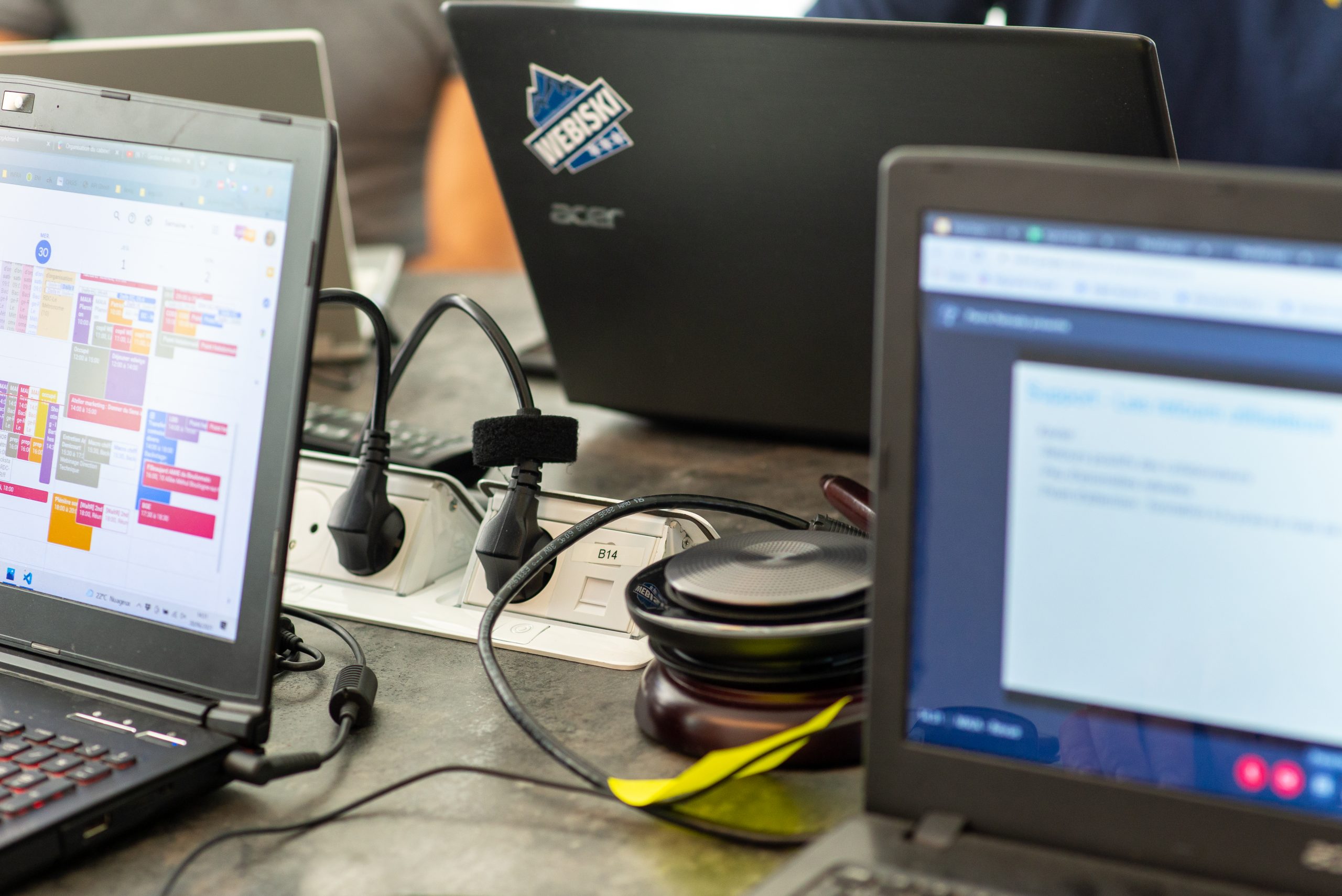 Plusieurs ordinateurs portables affichent des applications et sont branchés sur des prises sur la table de réunion